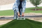 A landscaping expert, pulling a long section of artificial grass